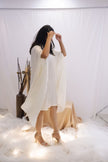 Woman wearing a white pleated dress in a minimalistic setting. Freo